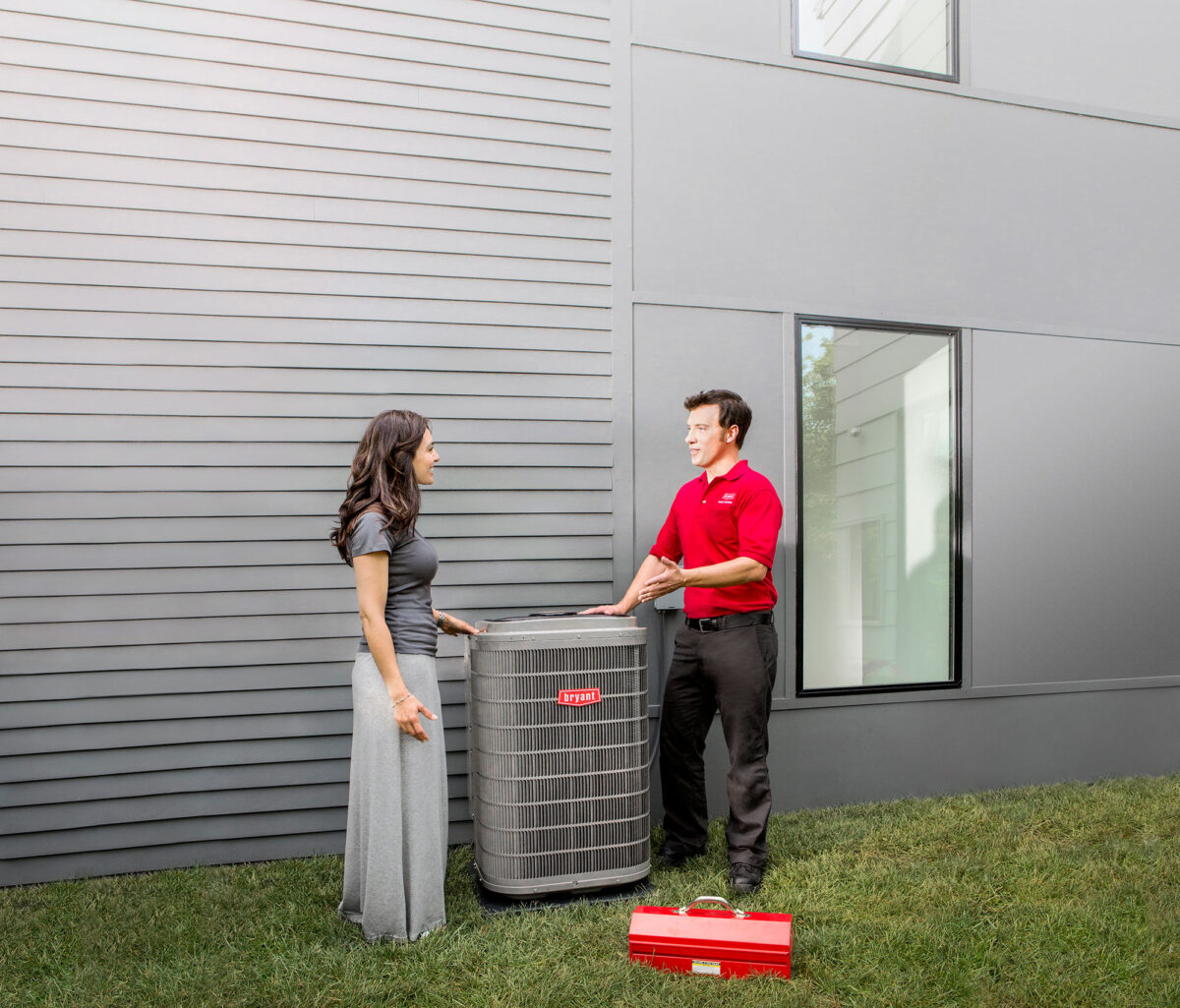 dealer with homeowners discussing heat pump outdoors